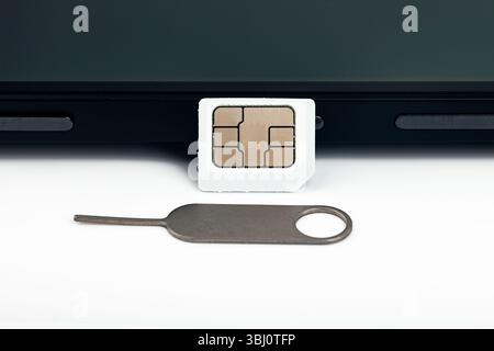 Close-up macro shot of inserting sim card with ejector tool into a smartphone Stock Photo