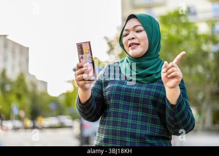 Muslim woman having video call via mobile phone in the city Stock Photo