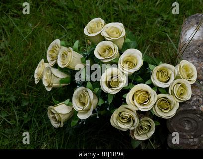 Eighteen artificial rose flowers on a grave, UK Stock Photo