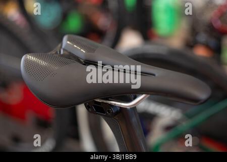 Detail of the sport saddle for bicycle. Elegant black and white racing saddle on the seat post, close-up.Racing bike. Stock Photo