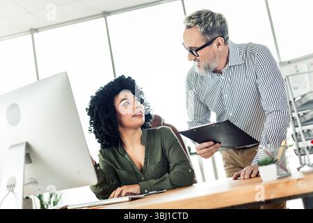 Coworkers interacting in a modern office space promoting teamwork and diversity, showcasing positive collaboration Stock Photo