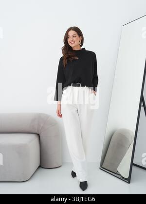 Brunette female model showcases stylish fashion in a modern studio setting Stock Photo