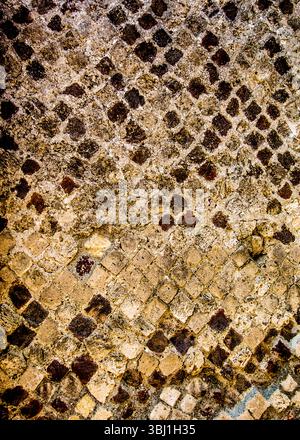 A close-up shot of a textured surface, likely a mosaic or tiled wall, with a pattern of diamond-shaped tiles in varying shades of brown and beige. The Stock Photo