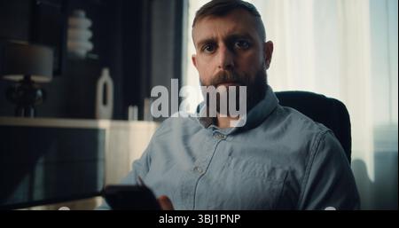Professional Financial Expert Working on Smartphone, Monitoring Real-Time Stocks, Exchange Market Charts, Looking at Camera. Portrait of Successful Businessman in Comfortable Office of Investment Bank Stock Photo