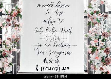 Photo of a real wedding venue with floral decorations and a romantic backdrop featuring “I love you” written in multiple languages. Stock Photo