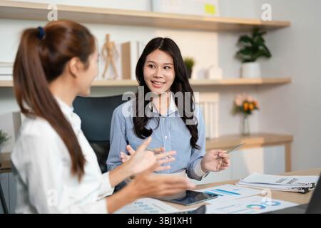 Dynamic Team Collaboration. Two women engaging in financial discussions at their workplace. Stock Photo