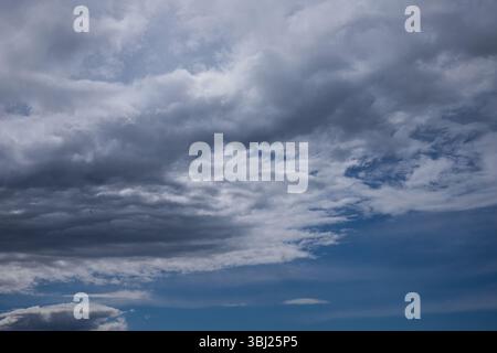 Ominous mammatus clouds form in the sky, signaling an approaching storm. The unusual pouch-like structures and dark gray tones create a powerful and e Stock Photo