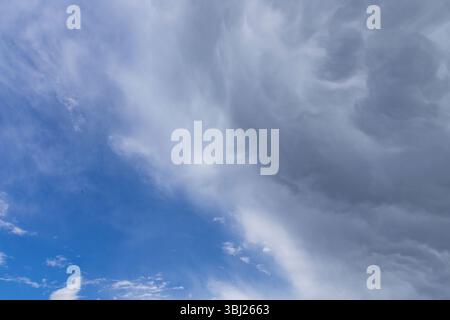 Ominous mammatus clouds form in the sky, signaling an approaching storm. The unusual pouch-like structures and dark gray tones create a powerful and e Stock Photo