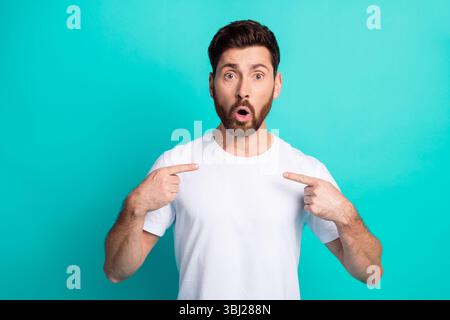 Surprised young man in white t-shirt makes gestures on turquoise background Stock Photo