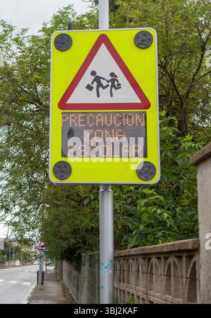 Signpost equipped with school warning message system. Spanish language: Warning school area Stock Photo