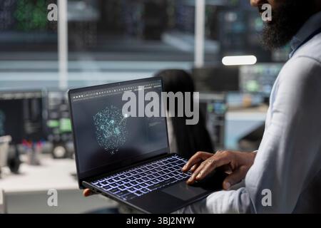 Close up of data center engineer using laptop to implement AI virtualization frameworks, improving resource allocation. Server hub worker does artificial intelligence predictive analysis on notebook Stock Photo