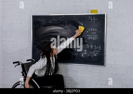 An Empowered Teacher in a Wheelchair Actively Engaging with Students in a Classroom Setting Stock Photo