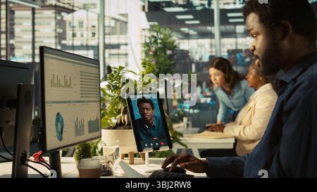 Worker in office talking with manager supervising tasks progression during online videocall. Employee discussing with supervisor overseeing work done during remote teleconference meeting, camera B Stock Photo