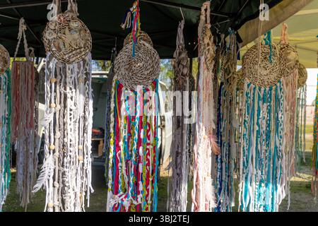 Denia, Alicante - Spain - 12-01-2024: Handmade dreamcatchers with braided fabric, shells, beads, and feathers, hanging from a tent, displaying various Stock Photo