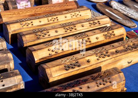Jalon, Alicante - Spain - 12-14-2024: A collection of handcrafted wooden incense boxes with intricate brass inlays, displayed on a blue fabric surface Stock Photo