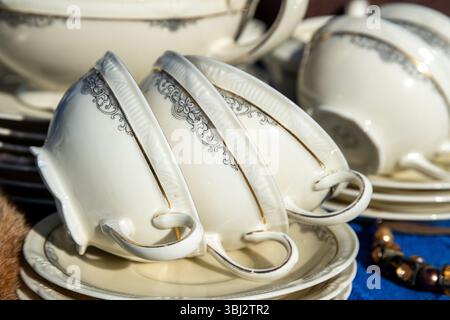 Jalon, Alicante - Spain - 12-14-2024: Three vintage porcelain tea cups with intricate black floral patterns and gold trim, stacked on matching saucers Stock Photo