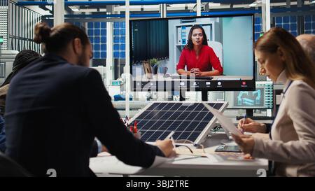 Factory engineers doing online videocall to refine designs for increased energy output using data. Photovoltaics plant specialists design solar cell prototypes in teleconference meeting, camera A Stock Photo