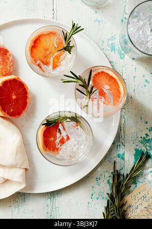 Iced grapefruit cocktails garnished with rosemary on white tray Stock Photo