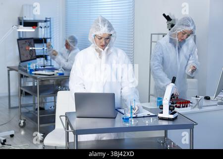 Scientists working with computers and samples in laboratory Stock Photo
