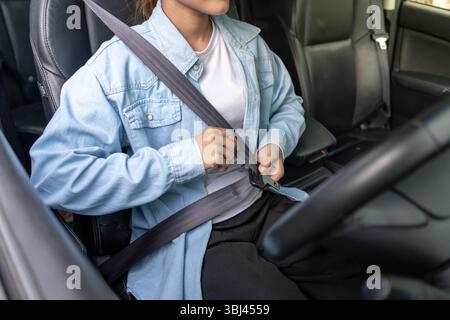 Woman use seatbelt and drives with intent, safe driving, driving practice, cheerful woman sits comfortably in the driver's seat with her hand confiden Stock Photo