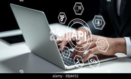 Businessman using a laptop while showing an icon of API. Tablet on the table. Technology innovation on a virtual screen. Concept of Application Progra Stock Photo