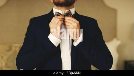 Wedding, fashion and hands of man with bow tie getting ready for event, ceremony and celebrate. Marriage, preparation and groom dressing in home with Stock Photo