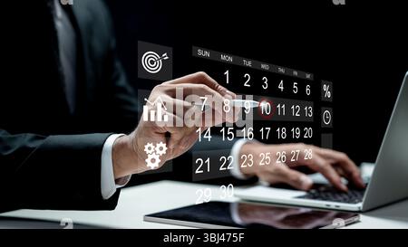 Businessman using a laptop while marking the date on a virtual calendar on a tablet screen. Technology innovation on a virtual screen. Concept of sche Stock Photo