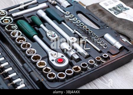 A wellstocked toolbox, brimming with various sockets and wrenches, rests on a sturdy wooden table, ready for any project Stock Photo