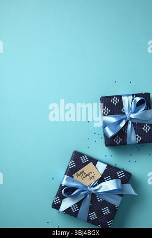 Happy Father's Day gift boxes! Two presents wrapped in patterned paper with blue ribbons and a greeting tag on a light blue background. Perfect for ce Stock Photo