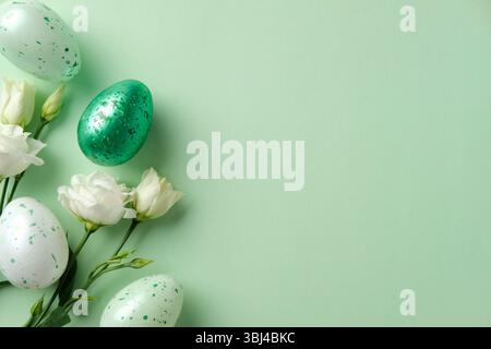 Happy Easter concept. White flowers and speckled Easter eggs on a pastel green background. Stock Photo