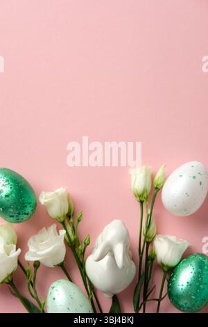 Easter flat lay composition. Pastel speckled eggs, white flowers, and a ceramic bunny on a soft pink background Stock Photo