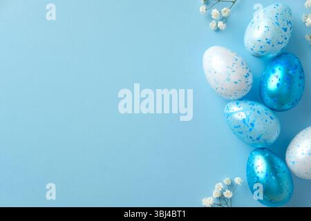 Aesthetic Easter flat lay composition with blue and white speckled eggs and small flowers on a light blue background. Stock Photo