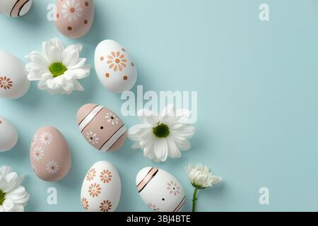 Floral Easter eggs and daisies on light blue background. Flat lay, top view, copy space Stock Photo