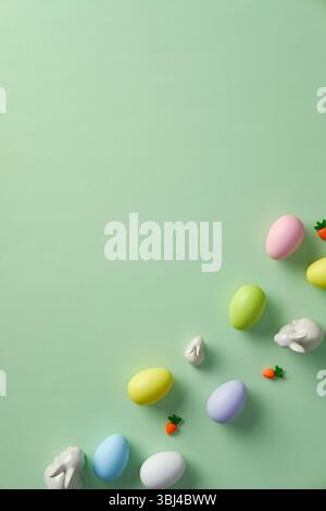 Easter flat lay composition. Top view pastel colored Easter eggs with ceramic bunnies on green background Stock Photo