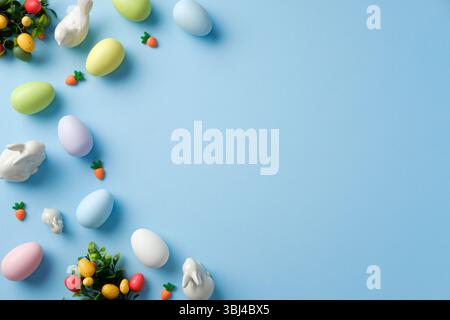 Easter flat lay composition with pastel colored Easter eggs, bunnies, decorations on blue background. Top view with copy space. Stock Photo