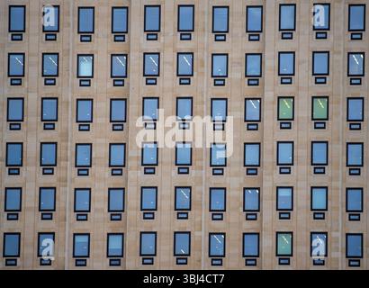 A close-up view of a modern building facade featuring a grid of rectangular windows. The windows are framed in black, with some reflections visible. Stock Photo