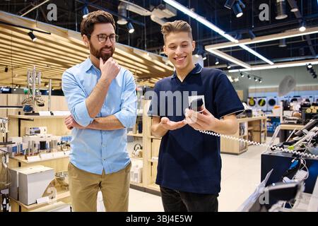 In a contemporary retail environment, a customer engages in a conversation with a store associate as they take their time exploring a variety of elect Stock Photo