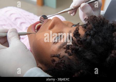 Dentist using dental instruments examining patient's teeth during checkup in dental clinic Stock Photo