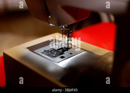 Close-up of sewing machine needle embroidering fabric on red background Stock Photo