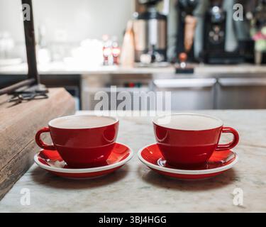 two red coffee cups on a countertop in a cafe in Stockholm Stock Photo