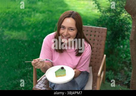 Woman in a pink t?shirt tasting a colored cake and smiling warmly Stock Photo