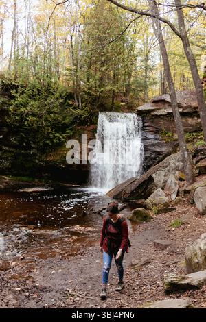 Mother carrying baby in front of a waterfall during Autumn Stock Photo
