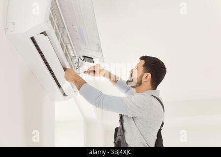 Male worker or handyman fixing air conditioning, working in repair service, using screwdriver Stock Photo
