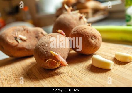 Sprouting potatoes and garlic on a kitchen wooden board Stock Photo