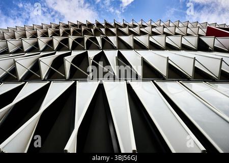 White triangular window shades creating a dynamic pattern on a contemporary building facade, showcasing innovative architectural design Stock Photo