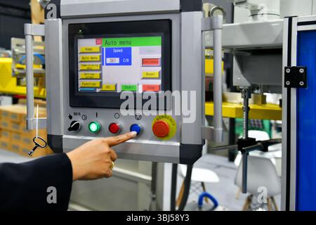 Machine operator hand turns on control panel of industrial machine. technician push button on control panel Stock Photo