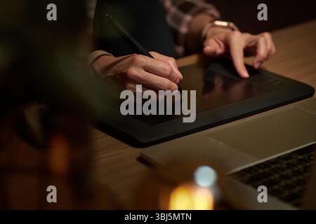 female hands with graphic tablet retouching photo on laptop computer at night Stock Photo