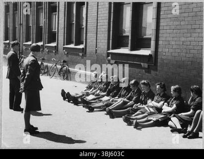Royal Air Force No. 2 School of Photography, Palatine Road, Blackpool, Lancashire, 1942-1943. Women's Auxiliary Air Force (WAAF) trainees receiving an open air lecture from RAF and WAAF instructors outside the No. 2 School of Photography. The RAF’s No. 2 School of Photography was established in August 1940 to meet the rapidly increasing need for more photographers and photographic technicians to aid with aerial reconnaissance during the WW2. The School was based at the Blackpool Technical College and Palatine Secondary School in Blackpool. Training of women at the School began in 1941. Stock Photo