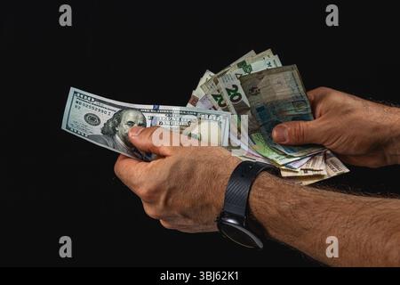 Two hands hold an assortment of banknotes from different countries, showcasing their exchange value in a visually striking manner against a dark backg Stock Photo