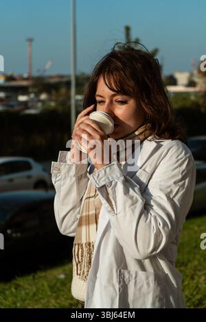 Doctor sips coffee while checking phone outside hospital Stock Photo